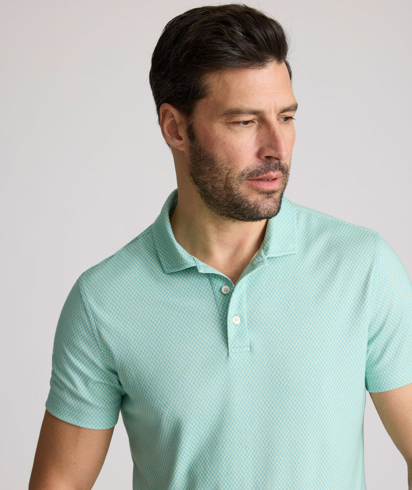 Model is wearing UNTUCKit Chen wrinkle free polo in bright green foulard print.