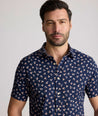 Model is wearing UNTUCKit Freeman performance short sleeve shirt in navy with orange floral shirt.