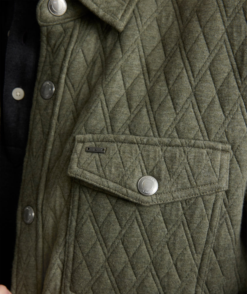 Model is wearing UNTUCKit Braunfield shirt jacket in beetle. 