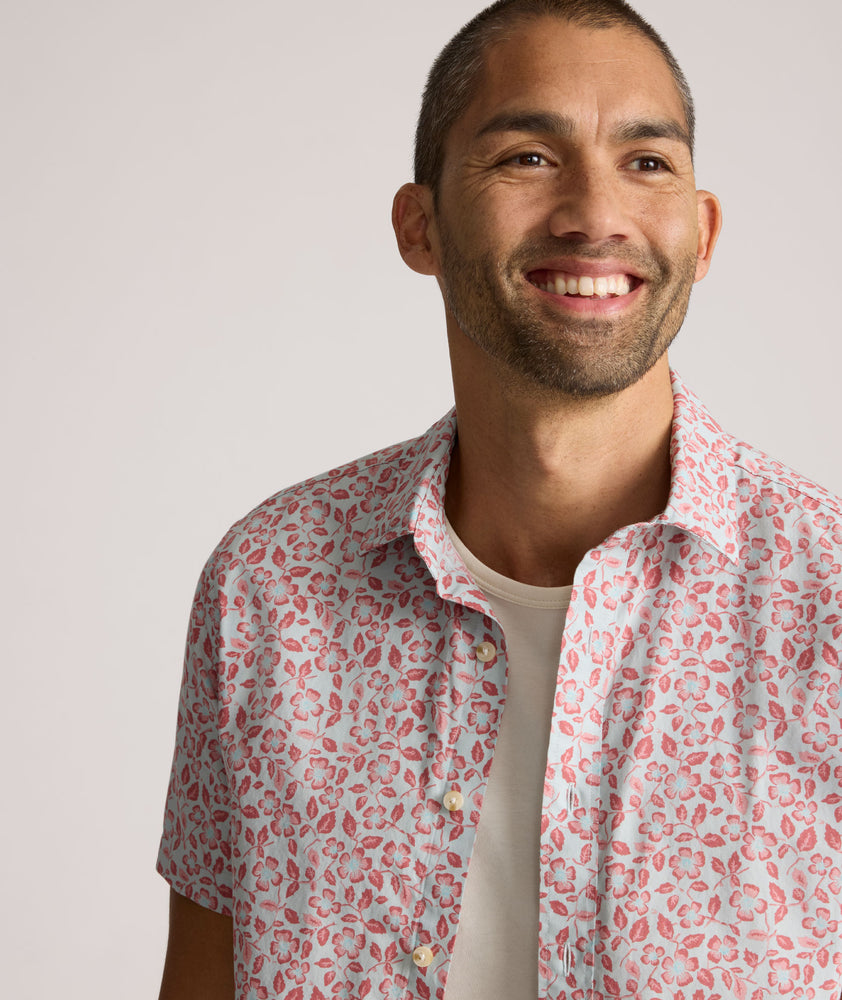 Model is wearing UNTUCKit buchanan short sleeve shirt in blue and rust floral. 