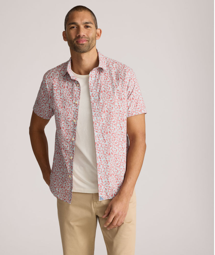 Model is wearing UNTUCKit buchanan short sleeve shirt in blue and rust floral. 