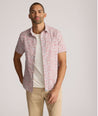 Model is wearing UNTUCKit buchanan short sleeve shirt in blue and rust floral. 