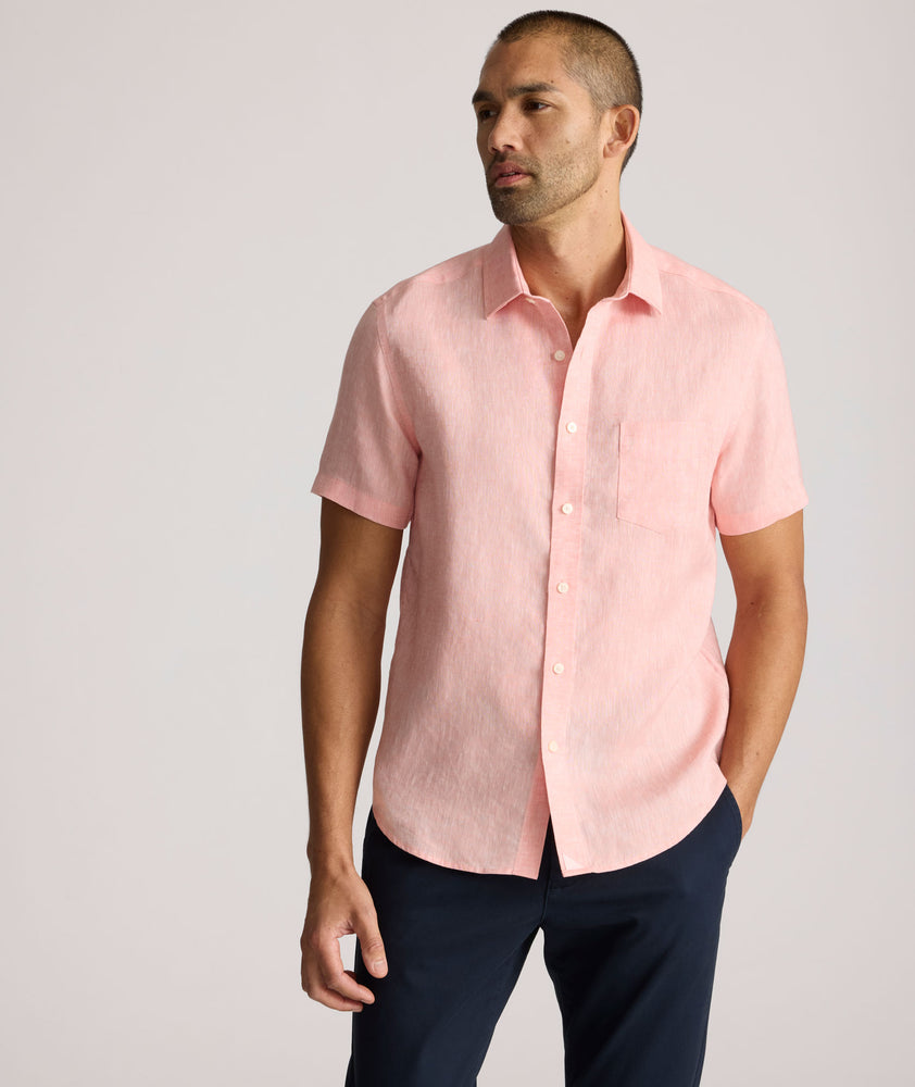 Model is wearing UNTUCKit solid coral haze cameron shirt. 