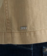 Model is wearing UNTUCKit chadwick herringbone over shirt in tan. 