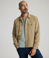 Model is wearing UNTUCKit chadwick herringbone over shirt in tan. 