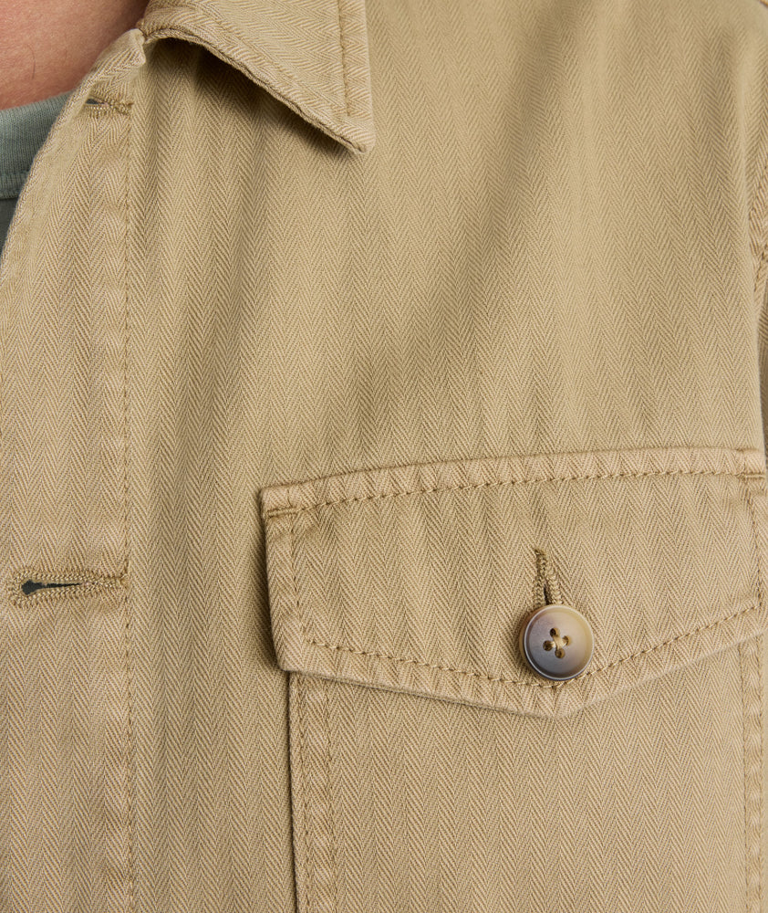 Model is wearing UNTUCKit chadwick herringbone over shirt in tan. 