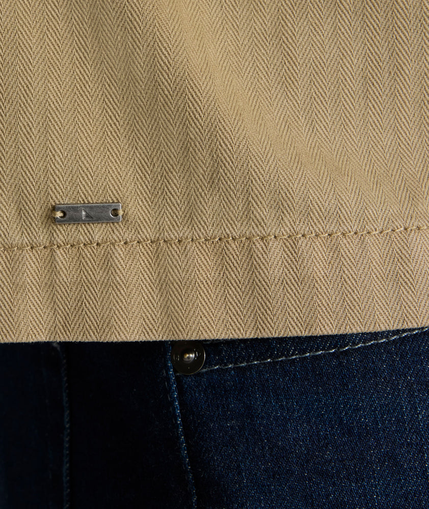 Model is wearing UNTUCKit chadwick herringbone over shirt in tan. 