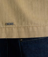 Model is wearing UNTUCKit chadwick herringbone over shirt in tan. 