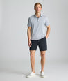 Model is wearing UNTUCKit 7" Traveler Tech Shorts in black. 