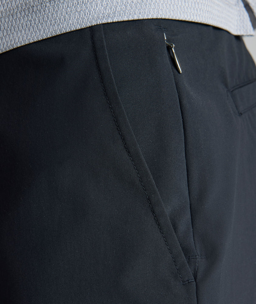 Model is wearing UNTUCKit 7" Traveler Tech Shorts in black. 