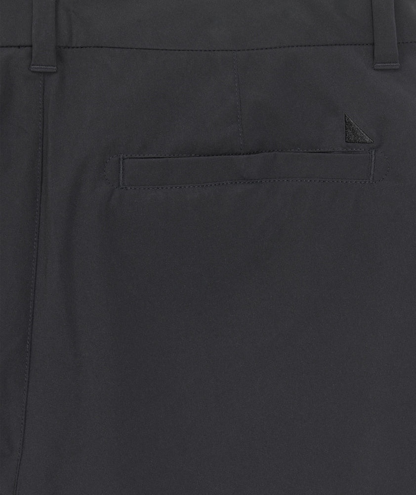 Model is wearing UNTUCKit 7" Traveler Tech Shorts in black. 