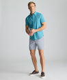 Model is wearing UNTUCKit 7" Traveler Tech Shorts in gray. 
