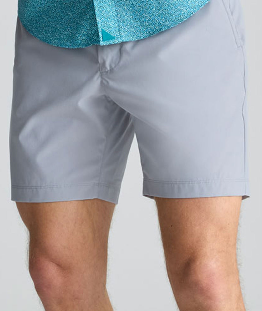 Model is wearing UNTUCKit 7" Traveler Tech Shorts in gray. 