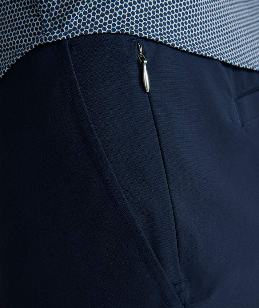 Model is wearing UNTUCKit 7" Traveler Tech Shorts in navy. 