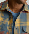 Model is wearing UNTUCKit Brushed Overshirt in Gray, Yellow, & Orange Plaid.