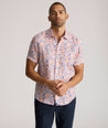 Model is wearing UNTUCKit Ellsworth Short Sleeve shirt in orange and blue floral. 