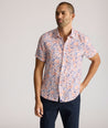 Model is wearing UNTUCKit Ellsworth Short Sleeve shirt in orange and blue floral. 