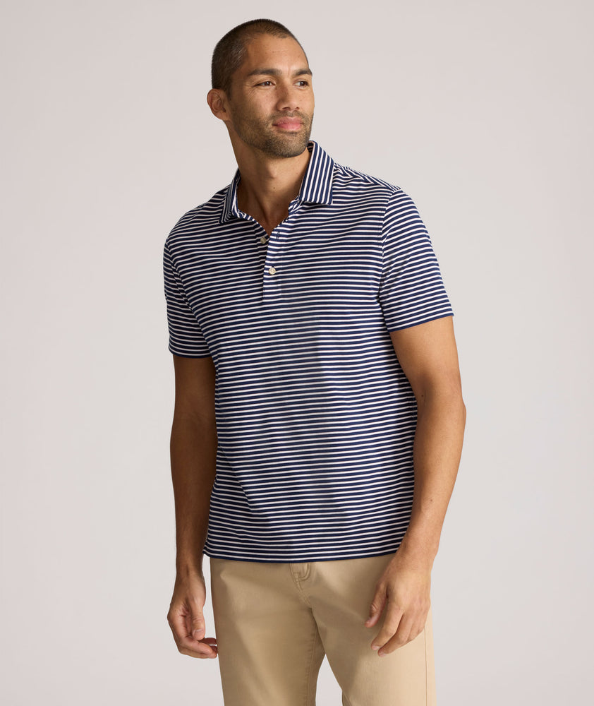Model is wearing UNTUCKit Fernandez Striped Performance Polo in Blue Print.