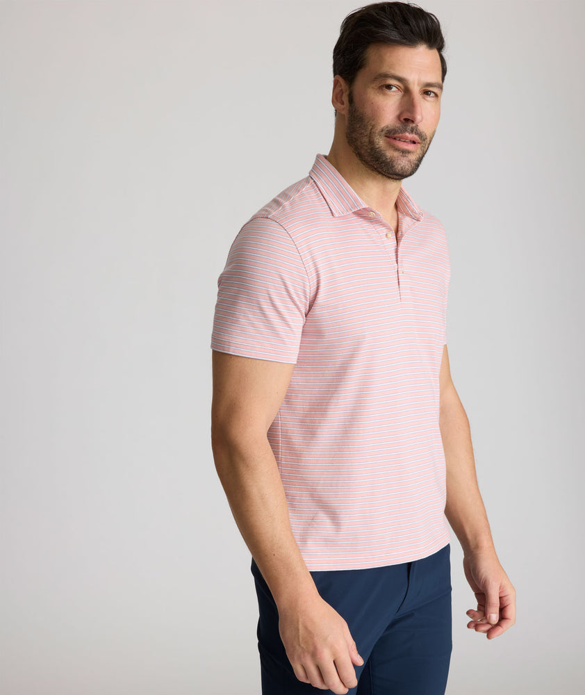 Model is wearing UNTUCKit Fernandez Striped Performance Polo in Pink Quartz.