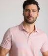 Model is wearing UNTUCKit Fernandez Striped Performance Polo in Pink Quartz.