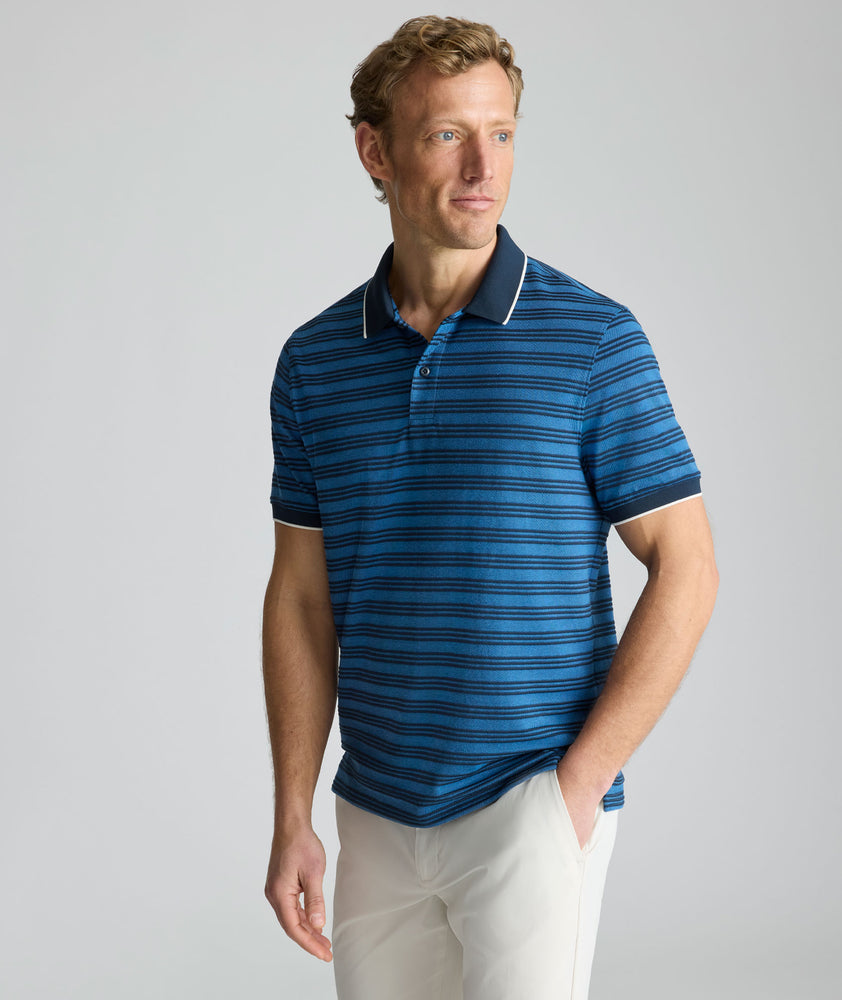 Model is wearing UNTUCKit Performance Hybrid Polo in dark blue. 