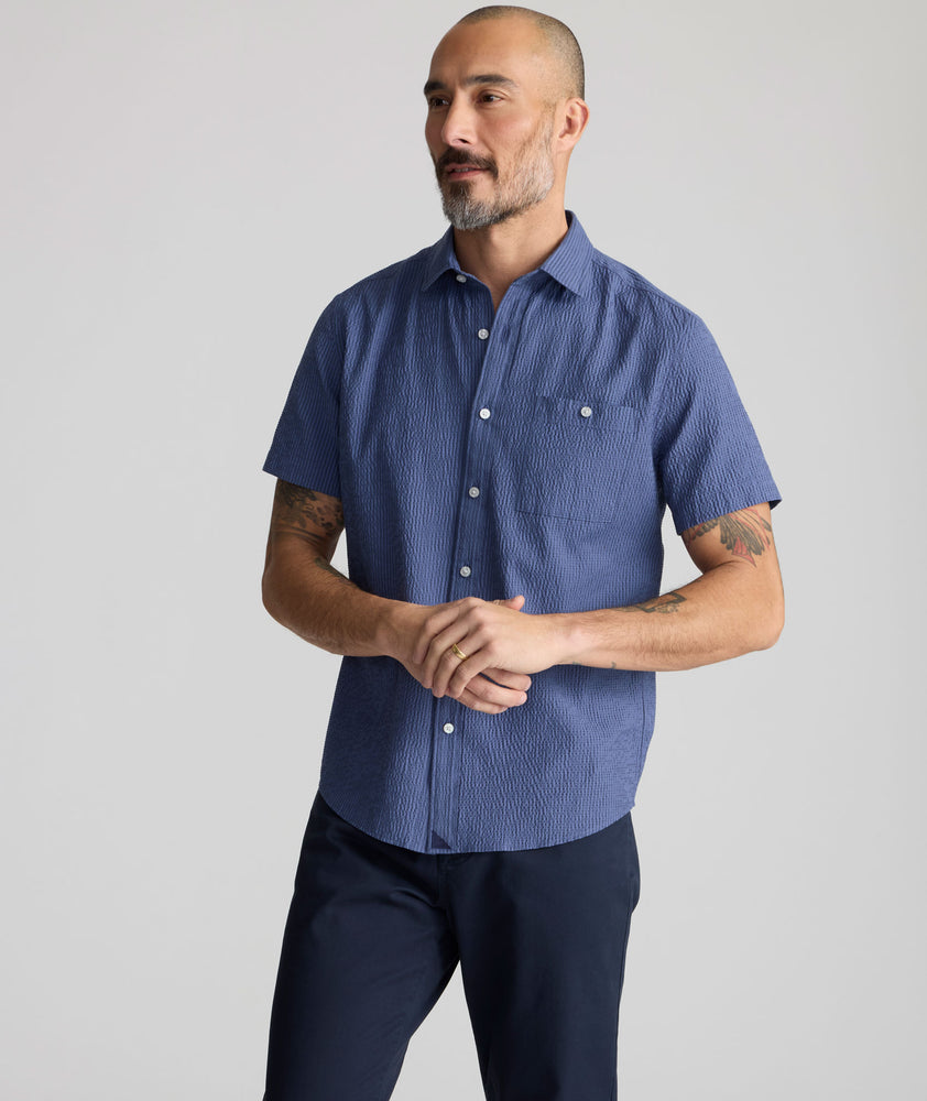 Model is wearing UNTUCKIt Performance Seersucker Short-Sleeve Shirt in dark blue. 
