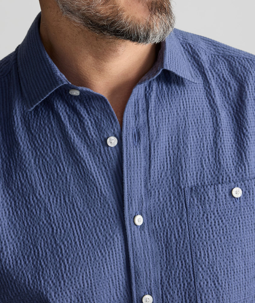 Model is wearing UNTUCKIt Performance Seersucker Short-Sleeve Shirt in dark blue. 
