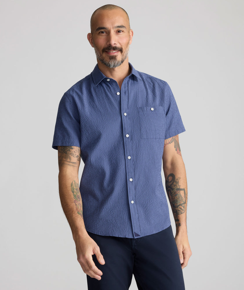 Model is wearing UNTUCKIt Performance Seersucker Short-Sleeve Shirt in dark blue. 