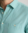 Model is wearing UNTUCKit Forbes performance seersucker short sleeve shirt in green. 