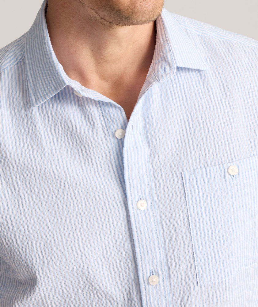 Model is wearing UNTUCKit Forbes performance seersucker short sleeve shirt in cerulean. 