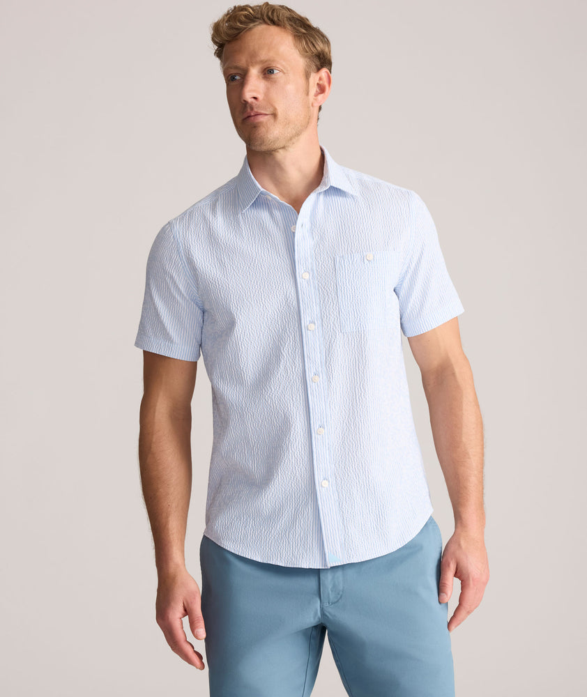 Model is wearing UNTUCKit Forbes performance seersucker short sleeve shirt in cerulean. 