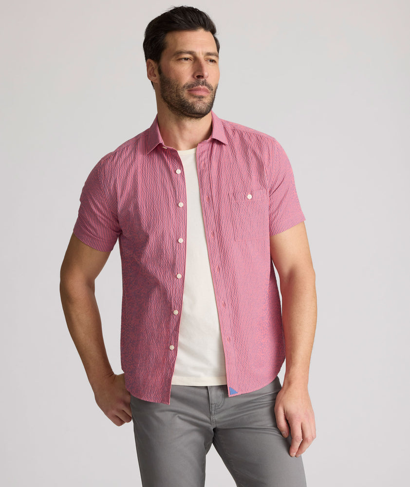 Model is wearing UNTUCKit Forbes performance seersucker short sleeve shirt in pink. 