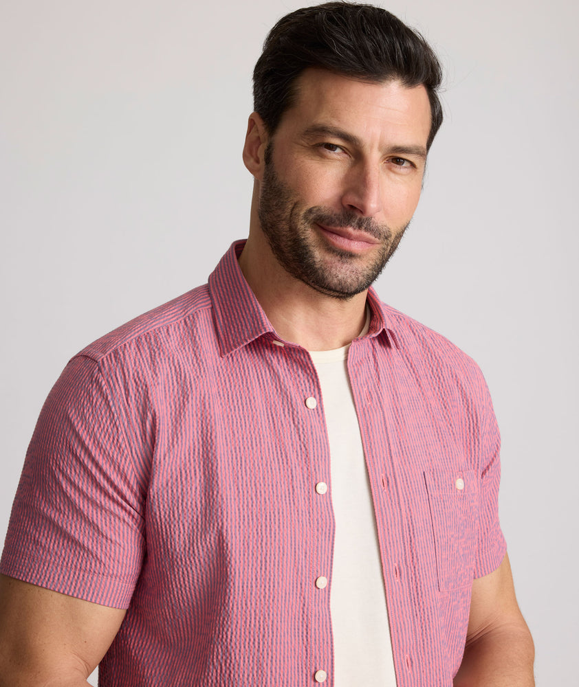 Model is wearing UNTUCKit Forbes performance seersucker short sleeve shirt in pink. 