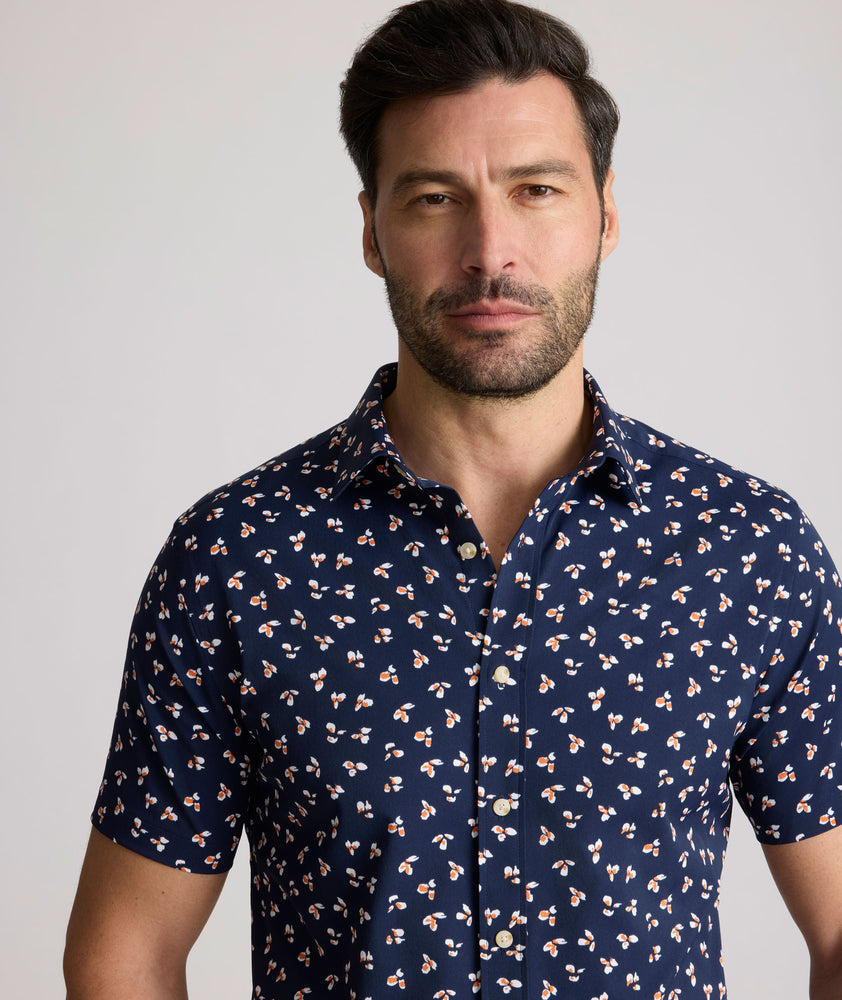 Model is wearing UNTUCKit Freeman performance short sleeve shirt in navy with orange floral shirt. 