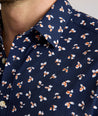 Model is wearing UNTUCKit Freeman performance short sleeve shirt in navy with orange floral shirt. 