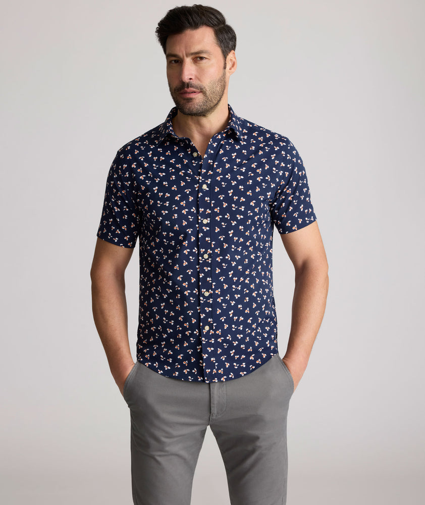 Model is wearing UNTUCKit Freeman performance short sleeve shirt in navy with orange floral shirt. 