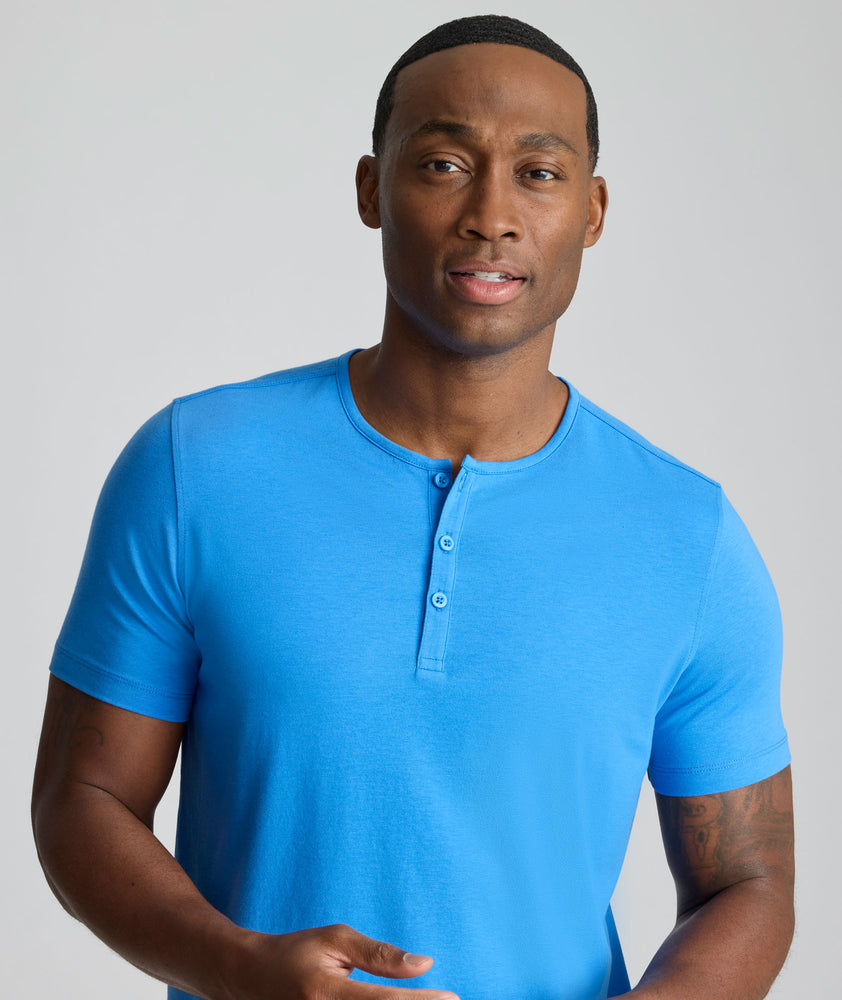 Model is wearing UNTUCKit EcoSoft Short-Sleeve Henley in light blue. 