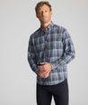 Model is wearing UNTUCKit Wrinkle-Free Hearthstead Shirt in blue and navy check. 