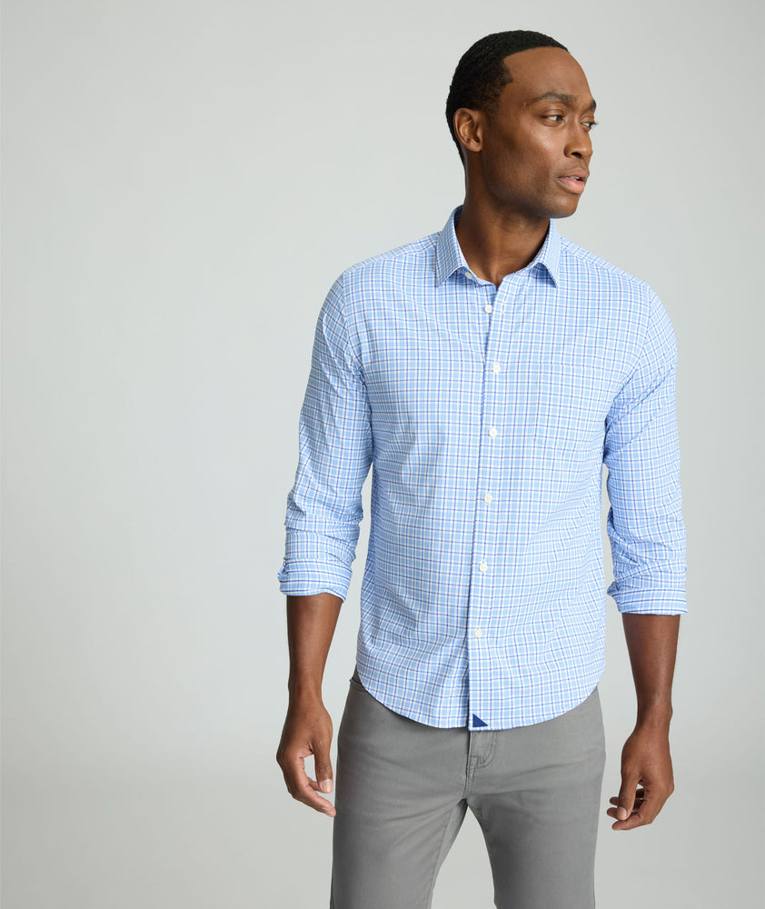 Model is wearing UNTUCKit Kaleb long sleeve performance shirt in light blue and white check. 