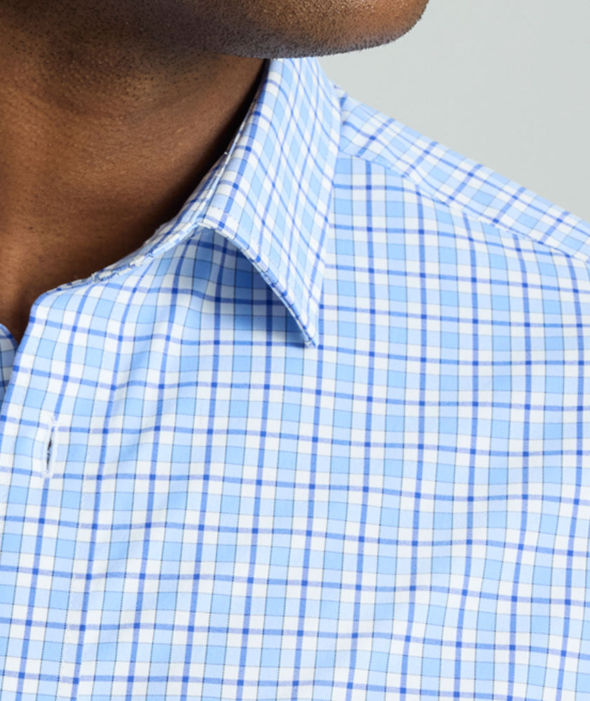 Model is wearing UNTUCKit Kaleb long sleeve performance shirt in light blue and white check. 