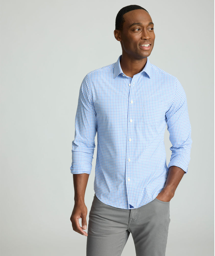 Model is wearing UNTUCKit Kaleb long sleeve performance shirt in light blue and white check. 