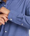 Model is wearing UNTUCKit King shirt in blue with small geo print. 