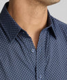 Man wearing a navy blue button-down shirt with a repeating geometric pattern, showing the collar, neck, and chest area.