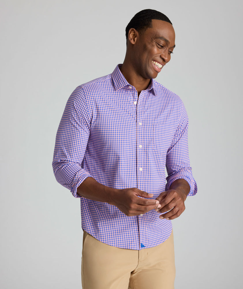 Model is wearing UNUCKit Quinby performance gingham button-down in pink. 