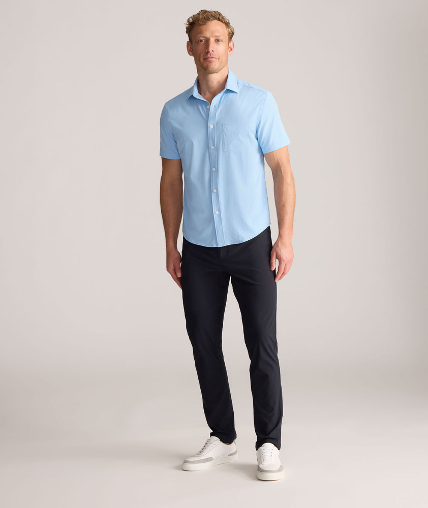 Model is wearing UNTUCKit Torre 5-Pocket Tech Pant in Black. 