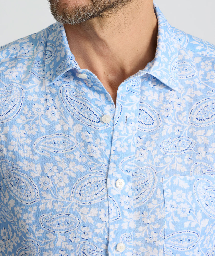 Model is wearing UNTUCKit Turner short sleeve linen shirt in light blue print. 