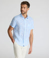 Model is wearing UNTUCKit Turner short sleeve linen shirt in light blue print. 