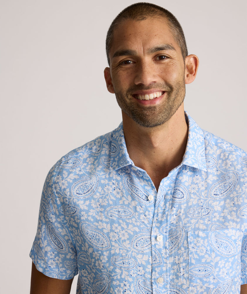 Model is wearing UNTUCKit Turner short sleeve linen shirt in light blue print. 