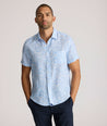 Model is wearing UNTUCKit Turner short sleeve linen shirt in light blue print. 
