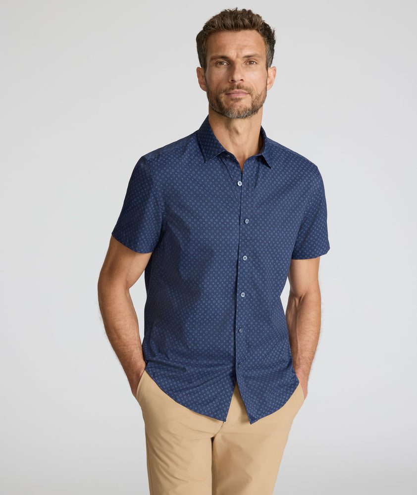 Model is wearing UNTUCKit Performance Short-Sleeve Vandelay Shirt in Navy Medallion Print.
